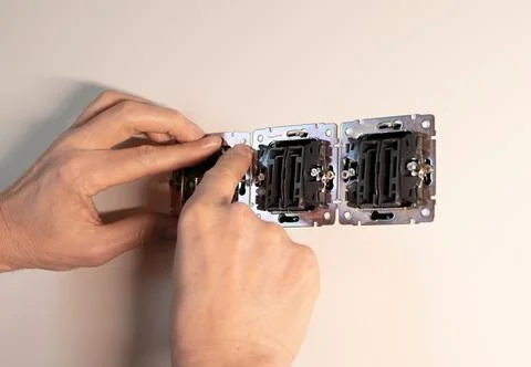 Electrician installing power socket mechanism into residential wall box. Ha.. Stock-Fotos