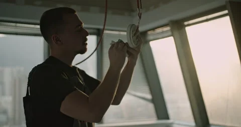 Electrician Installing Smoke Detector in Modern Office: Ensuring Fire Safety in Stock Footage 314140178