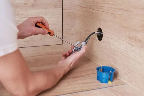 Electrician installing a socket plug in the kitchen. Renovation concept Stock Photos