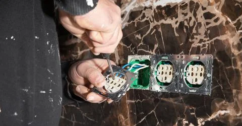 Electrician installing a wall socket at home. Stock Photos