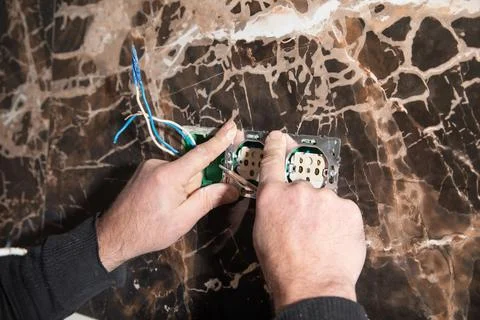Electrician installing a wall socket at home. Stock Photos