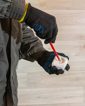 Electrician installing wall socket with screwdriver, close up of gloved hands 스톡 사진