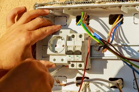 The electrician installs the socket into the electrical panel. Stock Photos
