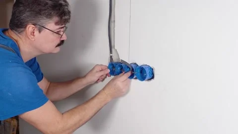 Electrician installs socket in a wall with an electric wire. Video stock 167784589