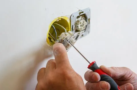 An electrician installs a socket in the wall. Stock Photos