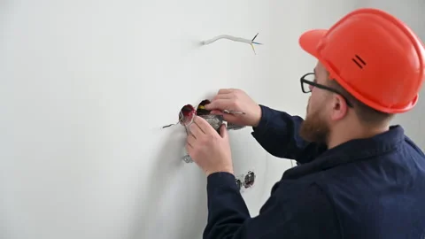 Electrician installs wall socket in unfinished interior Stock Footage 346541139