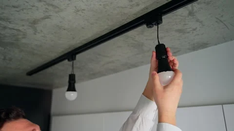 Electrician man changes a light bulb on modern track lighting Stock Footage 153291071
