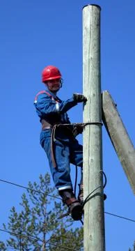 Electrician on a pole makes installation work Stock Photos