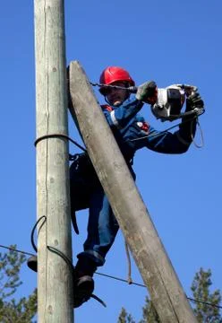 Electrician on a pole makes installation work Stock Photos