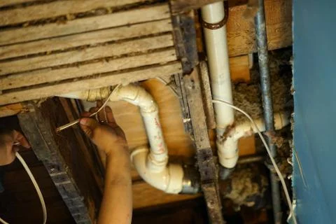 An electrician pulling wire through a hole in the ceiling. Stock Photos