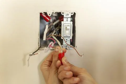 An electrician is replacing a wall switch. A DIY project concept. High voltag Stock Photos
