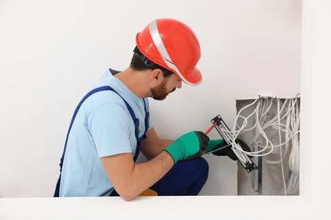 Electrician with screwdriver fixing patch panel indoors Foto stock