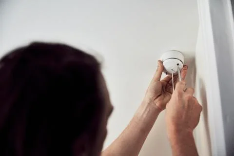 An electrician screwing the cap on a light fitting on the ceiling. Foto stock