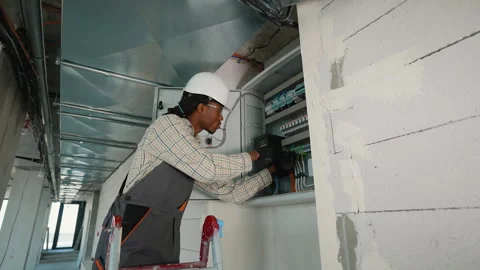 Electrician skillfully installing circuit breakers in industrial setting Stock Footage 312836887
