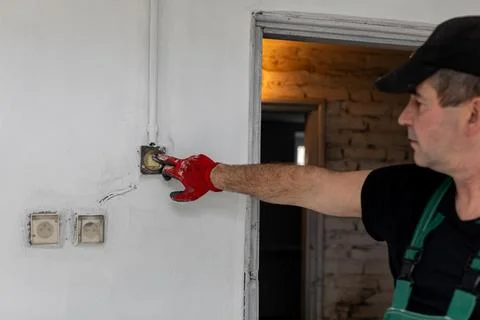 An Electrician Skillfully Installing a New Switch on the Wall in a Beautifully 写真素材