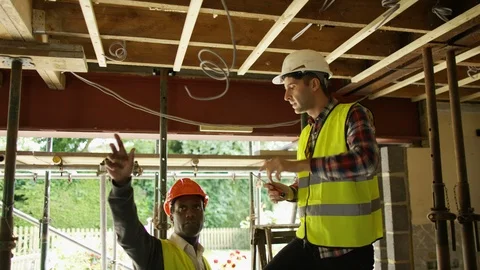 Electrician talking with site worker while doing wire fittings at site Stock Footage 108186177