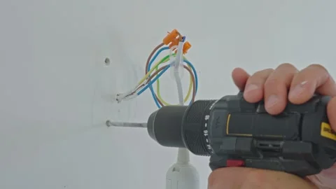 Electrician using power drill to make a hole close to exposed electrical wires Stock Footage 318180370