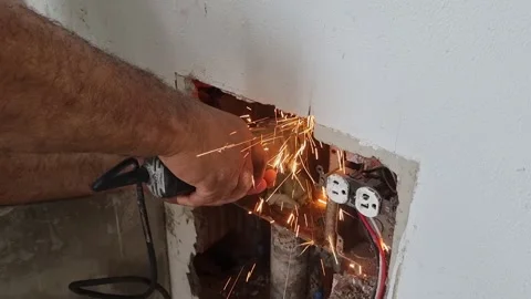 Electrician using a rotary tool to cut a wall near an electrical outlet Stock Footage 344969691