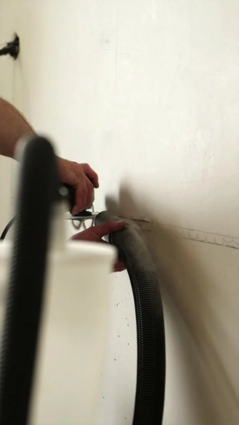 Electrician using vacuum cleaner during concrete wall drilling vertical Stock Footage 339298300