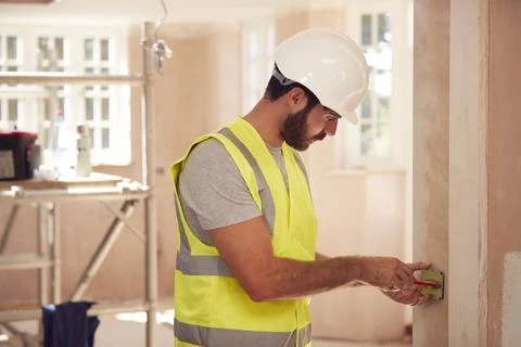 Electrician Wearing Hard Hat Fitting Light Switch At New Build Property Stock Photos