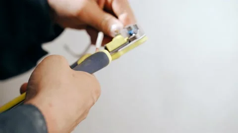 An electrician will use a tool to strip the insulation from the cable. Works on Video stock 154847550