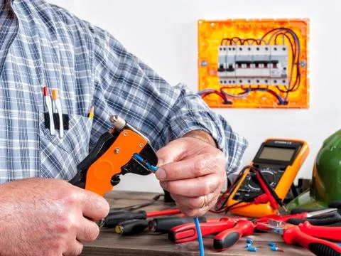 Electrician at work on cables with wire stripper. Foto stock