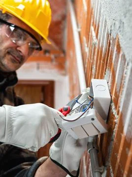 Electrician at work in an electrical system of a construction site. Construct Stock Photos