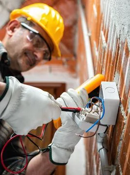 Electrician at work in an electrical system of a construction site. Construct Stock Photos