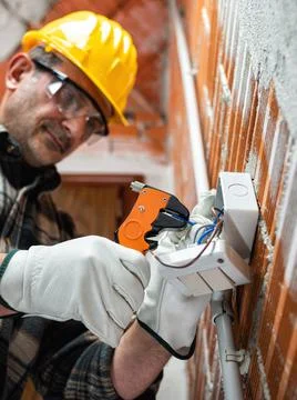 Electrician at work in an electrical system of a construction site. Construct Stock Photos