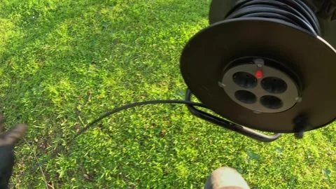 Electrician at work with power cable reel outdoors, preparing for electrical Stock Footage 313256448