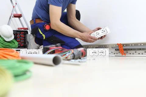 Electrician at work with socket in hand, install electric circuits, electrica Stock Photos