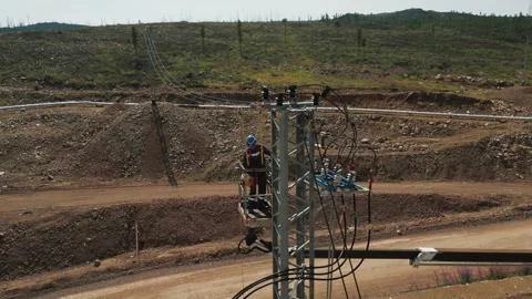 Electrician workers installating power line pylon using construction equipment Stock Footage 253985785