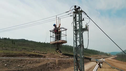Electrician workers installating power line pylon using construction equipment Stock Footage 253985811