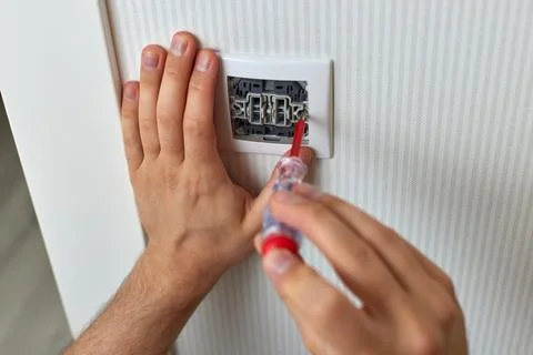 Electrician working on light switch using screwdriver Stock Photos