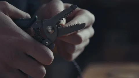 Electrician working on wiring using a pair of pliers to strip Stock Photos