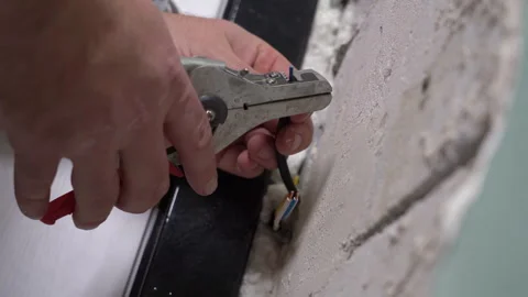 Electrician's hands remove the insulation from the electrical wires using pliers Stock Footage 264026386