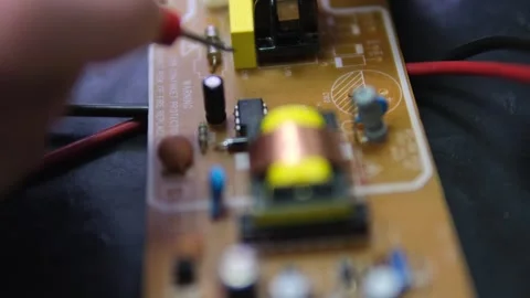 Electrician's hands testing a circuit board with a multimeter, measuring voltage Stock Footage 302352819