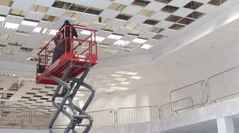 Electricians install ceiling lights using scissor lift in large building Stockbeeldmateriaal 65147119
