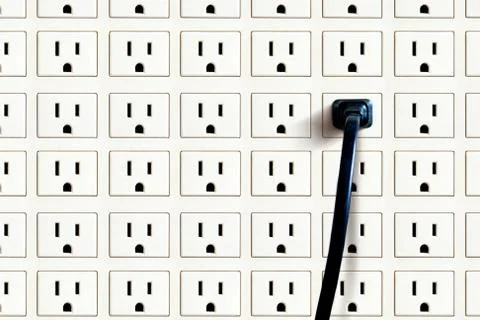 Electricity concept with a cable plugged in a full wall of contacts Stock Photos