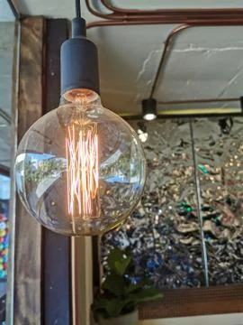 Electricity current inside a retro crystal clear light bulb. Stock Photos