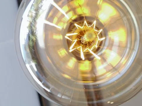 Electricity current inside a retro crystal clear light bulb. Stock Photos
