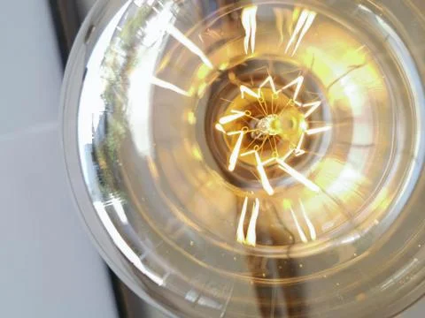 Electricity current inside a retro crystal clear light bulb. Stock Photos