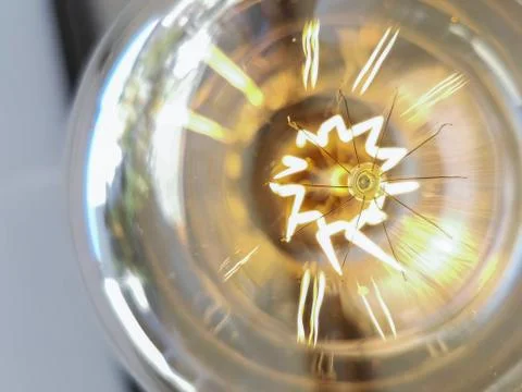 Electricity current inside a retro crystal clear light bulb. Stock Photos