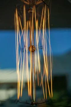 Electricity current inside a retro crystal clear light bulb. Stock Photos