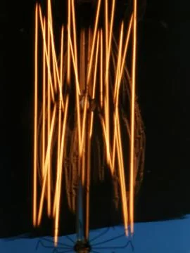 Electricity current inside a retro crystal clear light bulb. Stock Photos