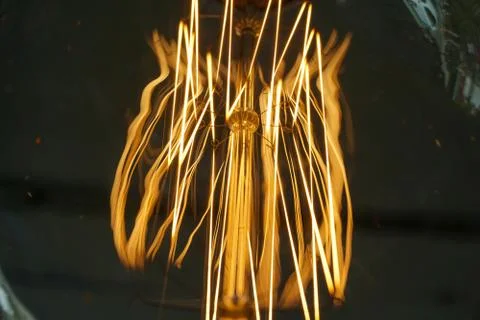 Electricity current inside a retro crystal clear light bulb. Stock Photos