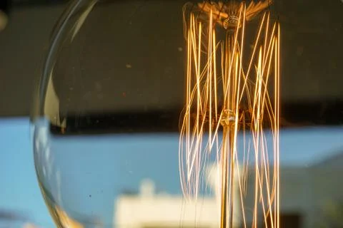 Electricity current inside a retro crystal clear light bulb. Stock Photos