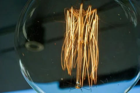 Electricity current inside a retro crystal clear light bulb. Stock Photos