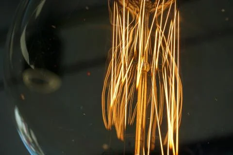 Electricity current inside a retro crystal clear light bulb. Stock Photos