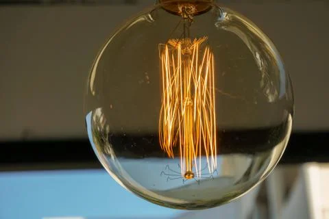 Electricity current inside a retro crystal clear light bulb. Stock Photos